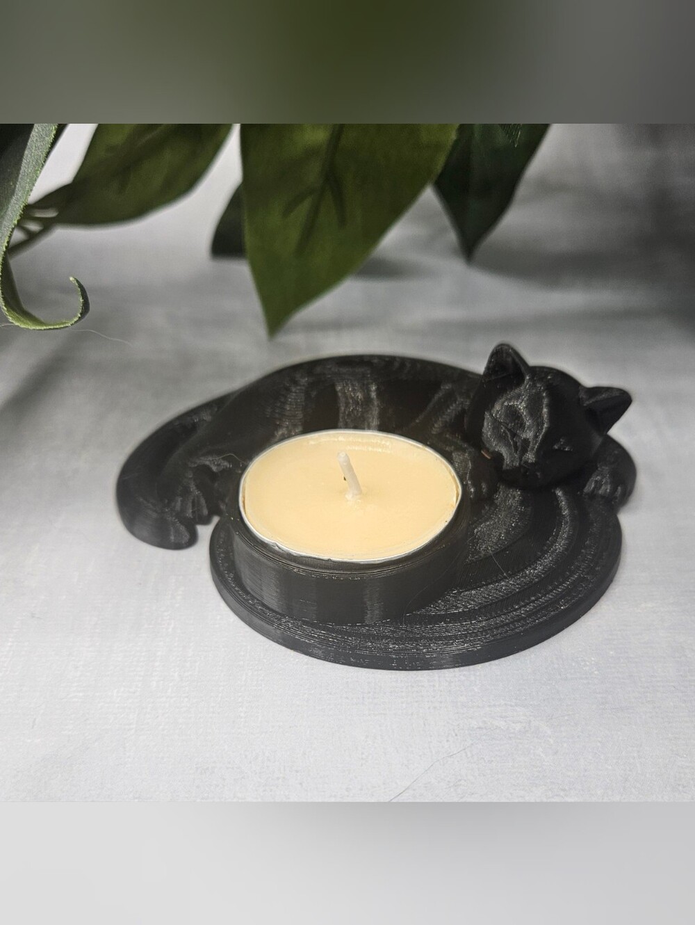 3D-printed black cat candle holder.It depicts a cute, sleeping or resting black